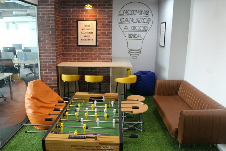 Colorful breakout area at Navratna Corporate Park with a foosball table, bean bags, and a brick feature wall.