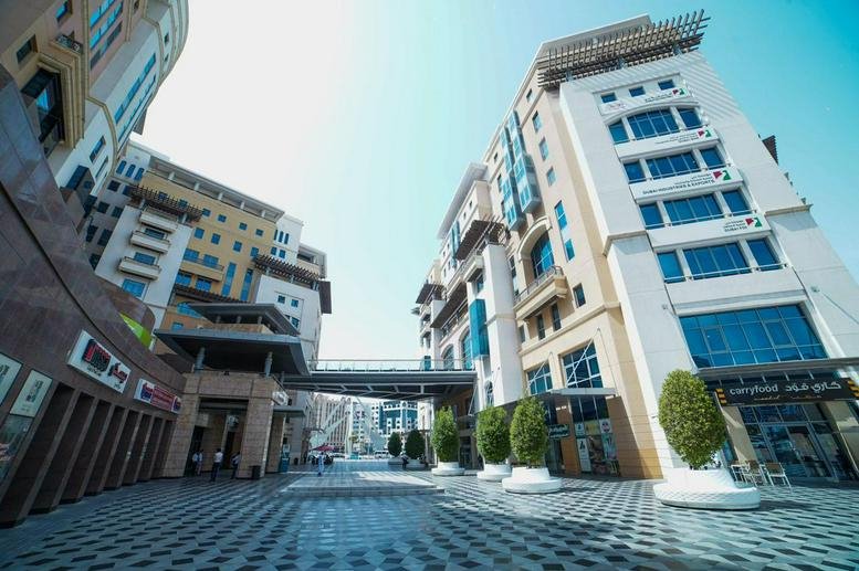 Exterior view of the Business Village Block A building complex with retail spaces and tiled walkways.