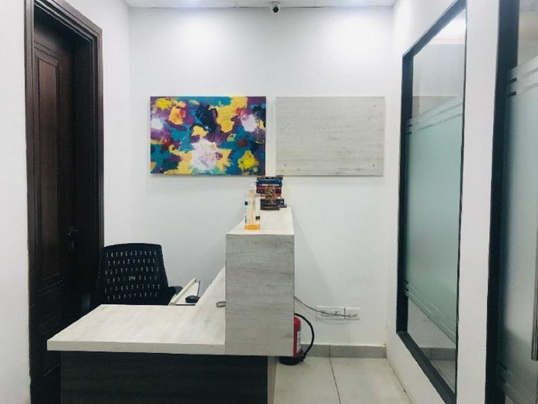 Bright reception area with a white marble-finish desk and colorful abstract art at C-177, Defence Colony, New Delhi.