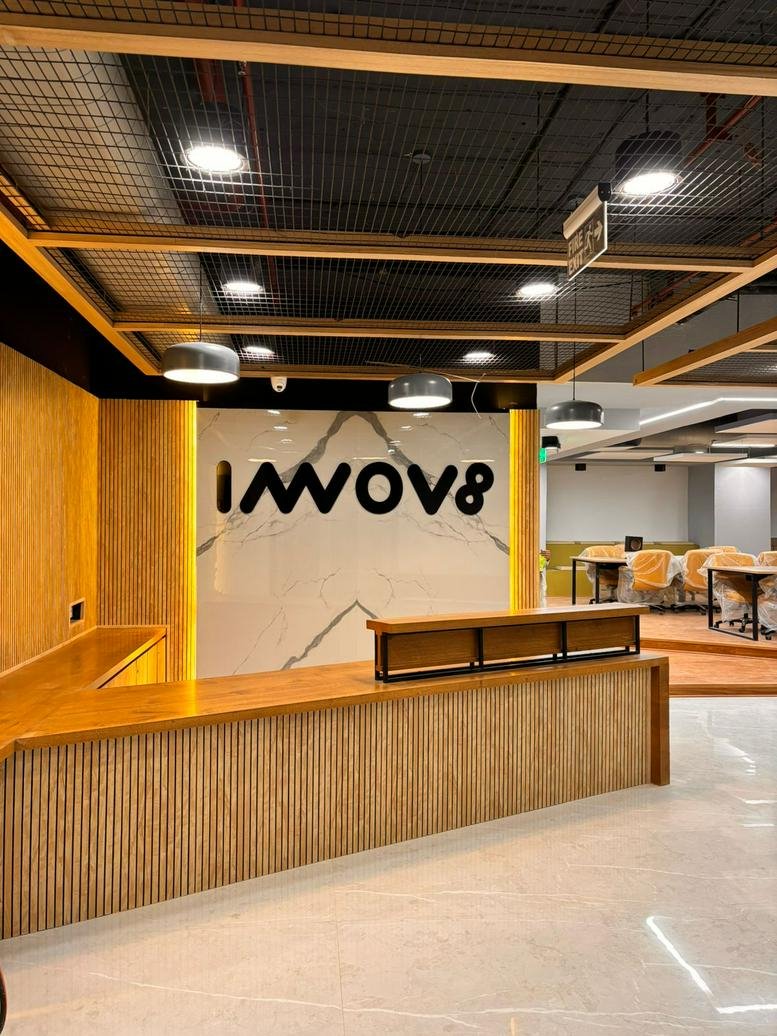 Modern reception lobby at DLF Cyber City with warm wood paneling and branded marble feature wall.