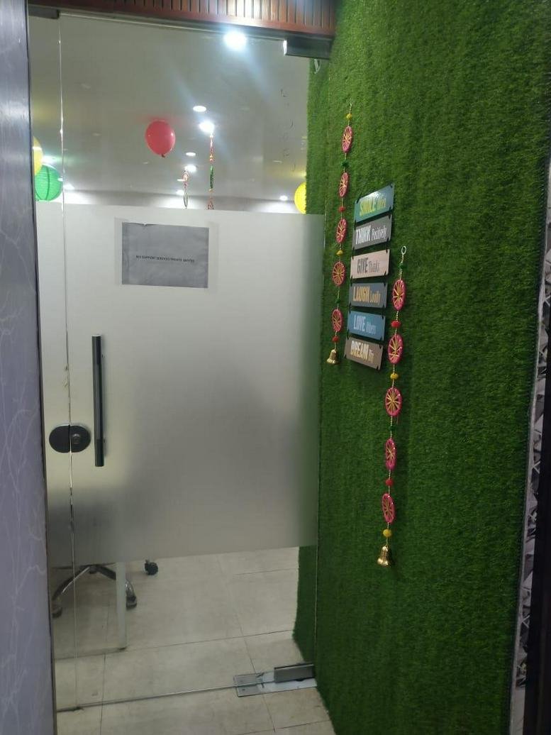 Entrance of E-10, 2nd Floor, Ram Dutt Enclave, Uttam Nagar, Delhi with a green turf feature wall and frosted glass door.