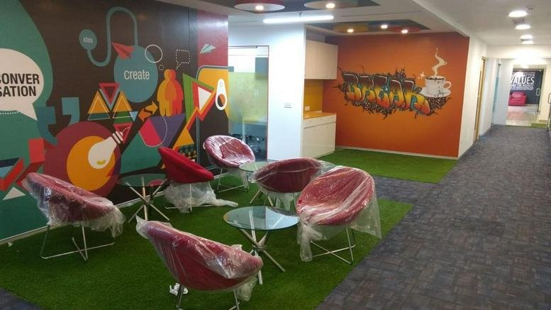 Spacious communal lounge at Express Trade Tower, 7th Floor, Sector 132, Noida, India with colorful wall art.