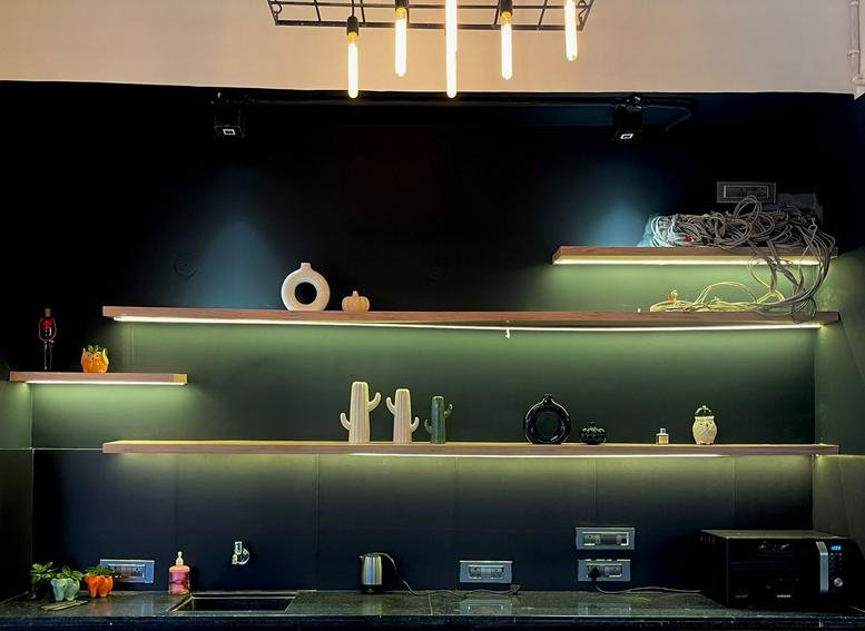 Warmly lit communal kitchen area at G3S Cinemas, Sector 11, Garg Trade Centre with open shelving and modern decor.