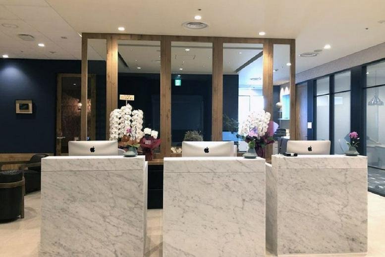 Elegant marble reception desks at the Gangnam Finance Center (L4) with orchid arrangements and wooden accents.