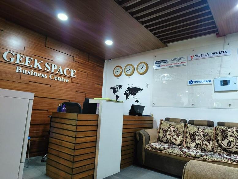 Wooden-paneled reception area of Geek Space Business Centre with a world map and comfortable seating.