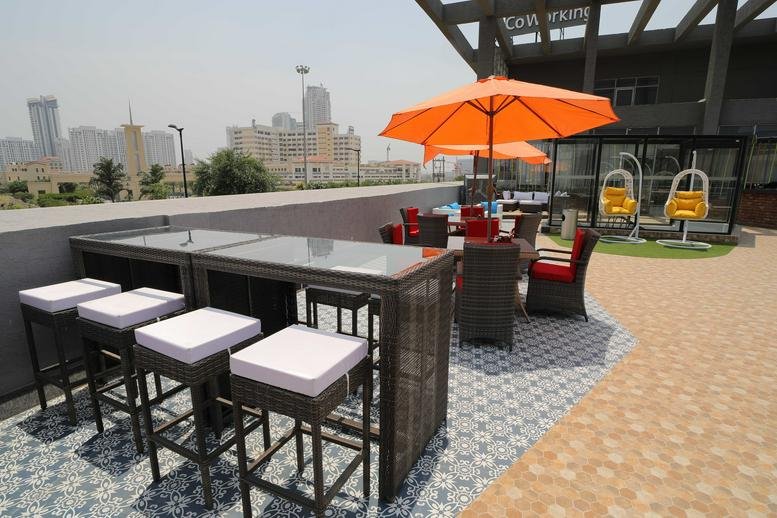 Rooftop patio with bar seating and orange umbrellas at Suncity Success Tower.