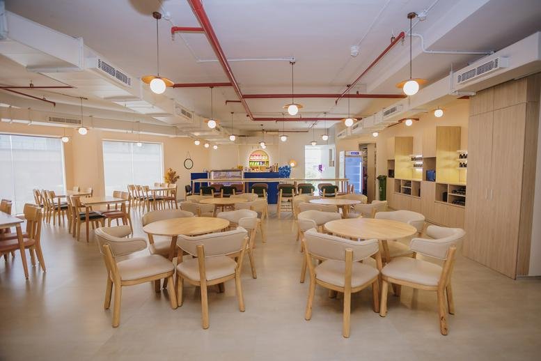 Spacious communal dining area with round wooden tables and modern pendant lighting at MPD Tower.