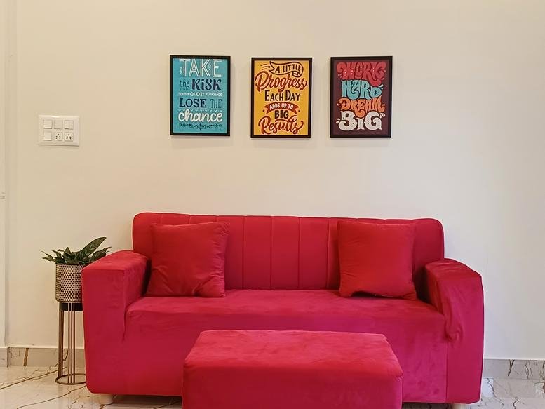 Lounge area at Industrial Suburb 2nd Stage, Mysuru featuring a red sofa and inspirational wall art.