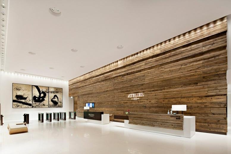 Main building entrance of K11 Atelier featuring a grand reclaimed wood wall and minimalist desk.