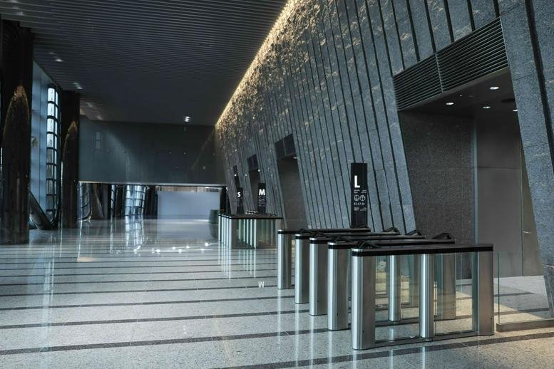 Modern lobby with glass security turnstiles and sleek grey stone walls.
