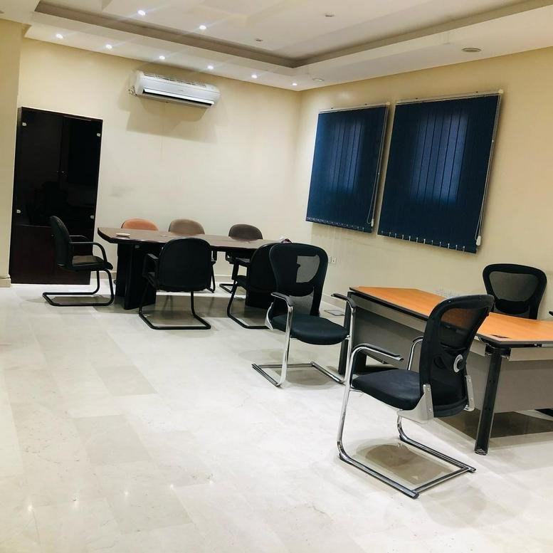 Meeting room at Building No. 6143 with black mesh chairs and a long conference table under bright lights.