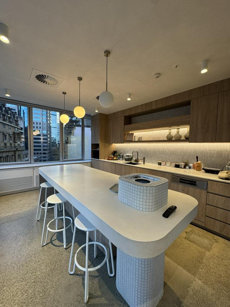 Modern communal kitchen at L12, 68 Pitt Street featuring a large island, wooden cabinetry, and city views.