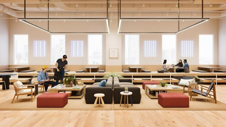 Modern open-plan lounge area at Links Umeda with tiered wooden seating and stylish armchairs.