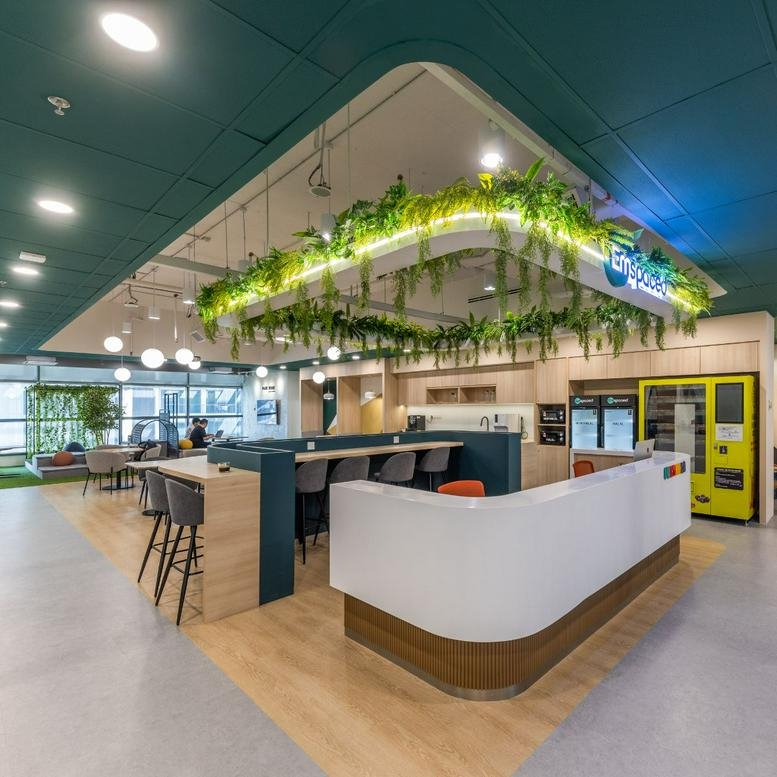 Spacious communal lounge at Mercu 3 featuring a modern white island, hanging plants, and a breakfast bar.