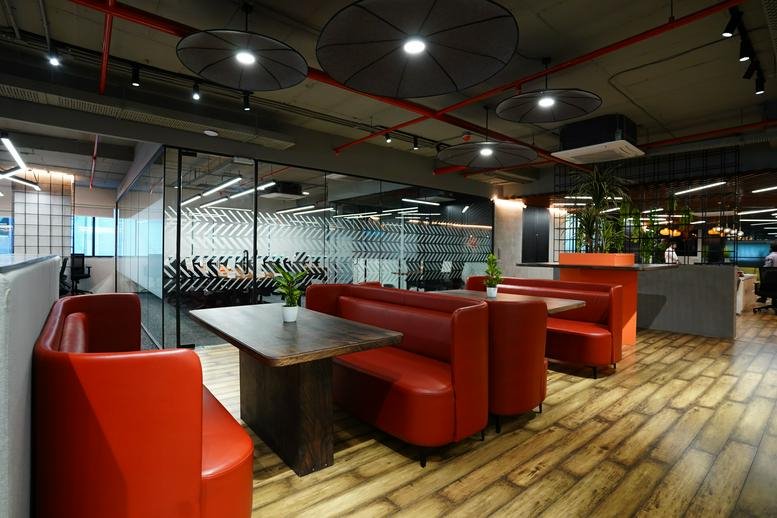 Vibrant communal lounge at Mahaveer Radiance with red booths, wooden floors, and industrial lighting.
