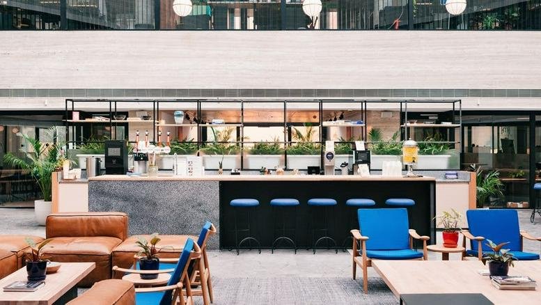 Spacious communal lounge and cafe area at Midosuji Frontier with leather sofas and a marble-topped bar.