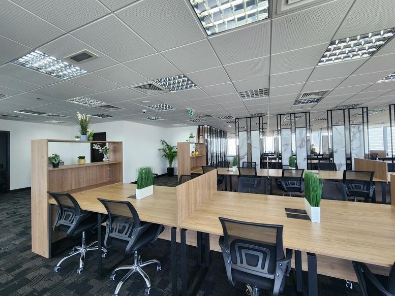 Open-plan workspace at Sky Tower Shams with wooden desks and ergonomic chairs.