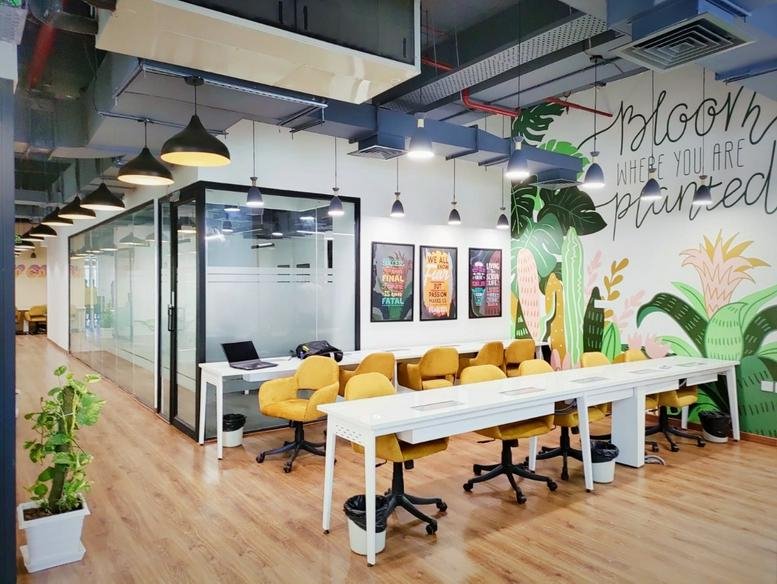 Spacious communal area at Innov8 CLC Tower with yellow chairs, wooden floors, and vibrant floral mural.