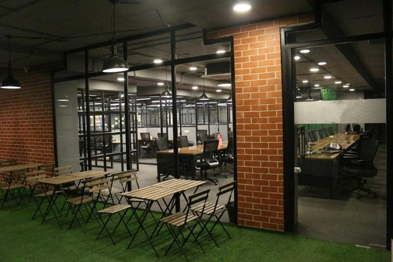 Spacious coworking space at Plot No. 255 with artificial turf flooring and brick feature walls.