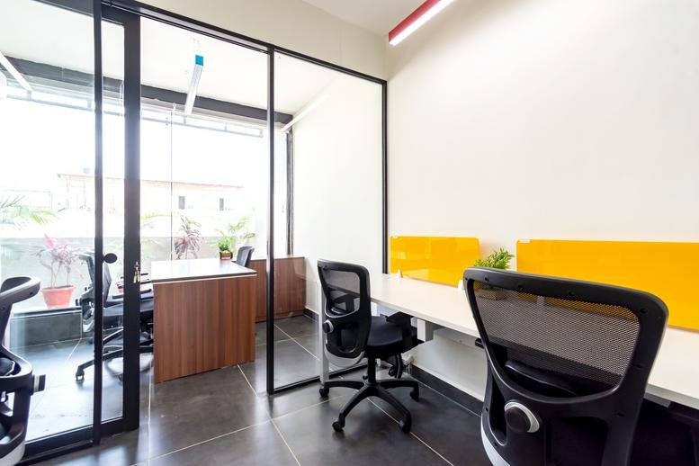 Bright private office with wood-finish desk and glass partition walls.