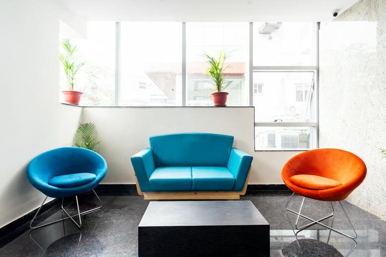 Breakout area at Plot No. 4/1, Survey No. 64, Huda Techno Enclave with blue and orange accent chairs.