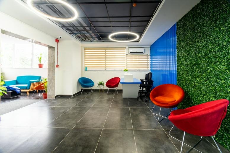 Wide-angle view of the Huda Techno Enclave office featuring colorful seating and a green wall.