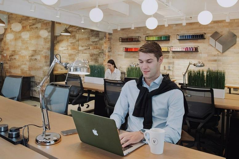Open-plan coworking area at Riley House, Room 904 featuring warm lighting and wood textures.