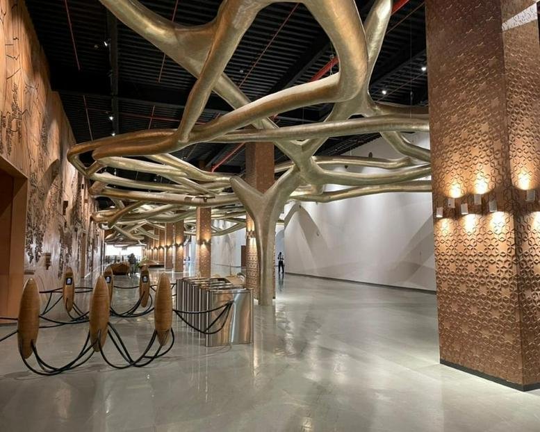 Spacious lobby featuring dramatic branch-like ceiling sculptures and warm brick pillars.