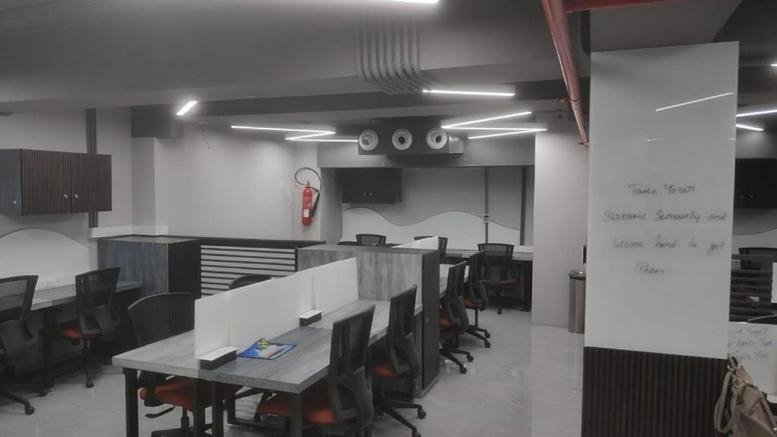 Modern open-plan office with grey workstations and red ergonomic chairs.
