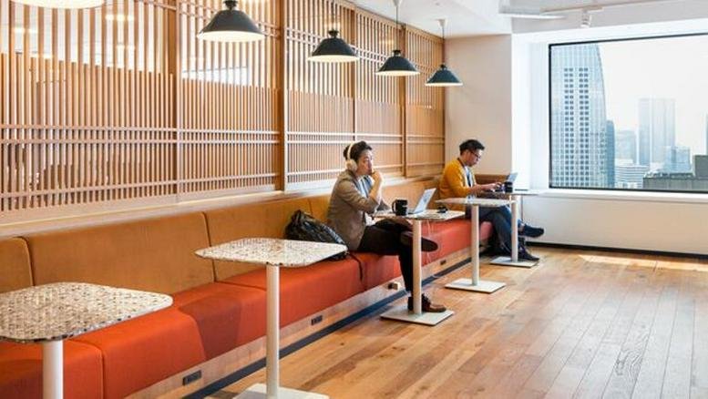 Modern communal lounge with orange booth seating and city views at Shiroyama Trust Tower.