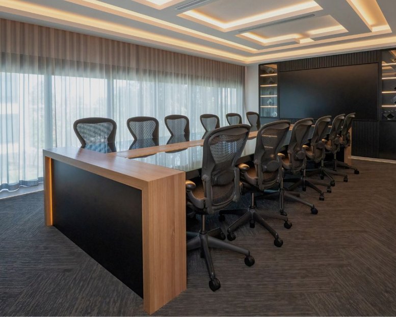 Spacious boardroom at Plug In Spaces, Unit 19, 153-155 Rooks Road featuring a large wood-trimmed table and mesh chairs.