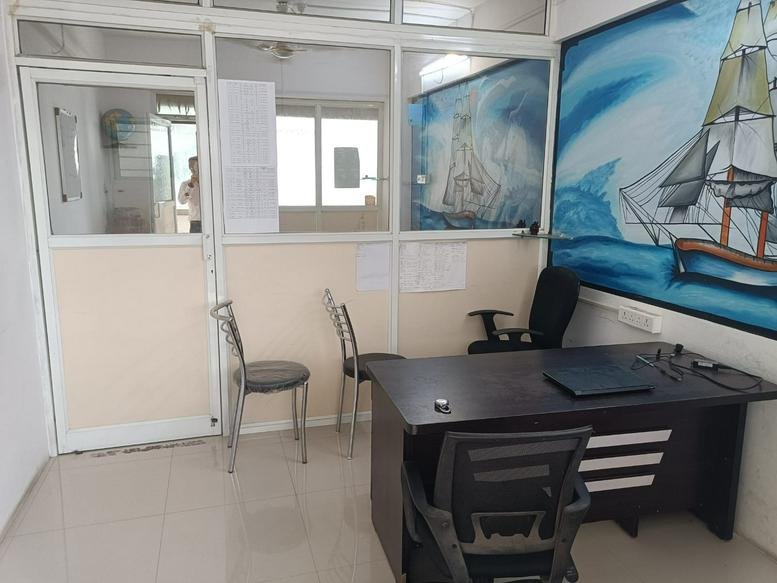 Bright office with a dark wood desk, seating area, and a large maritime wall mural.