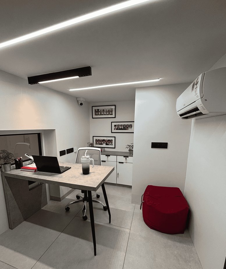 Private office with a grey desk, black laptop, and a red beanbag chair.