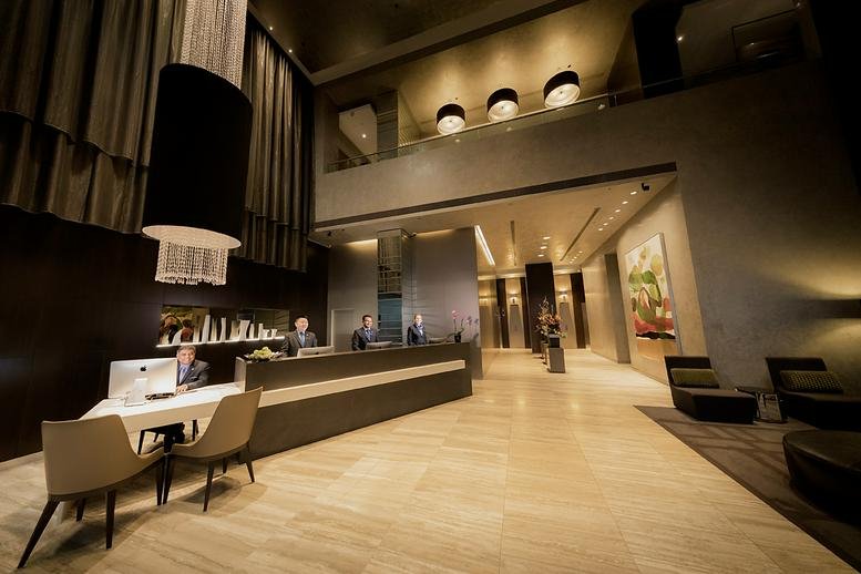Spacious reception lobby with warm lighting, polished floors, and a long dark service desk.