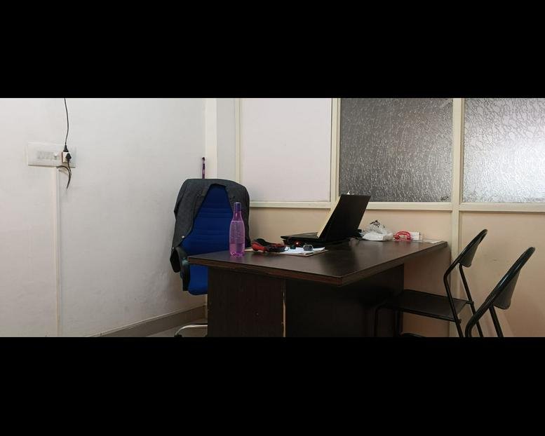 Private office space at 5 Nehru Road with a dark wood desk, laptop, and blue ergonomic chair.