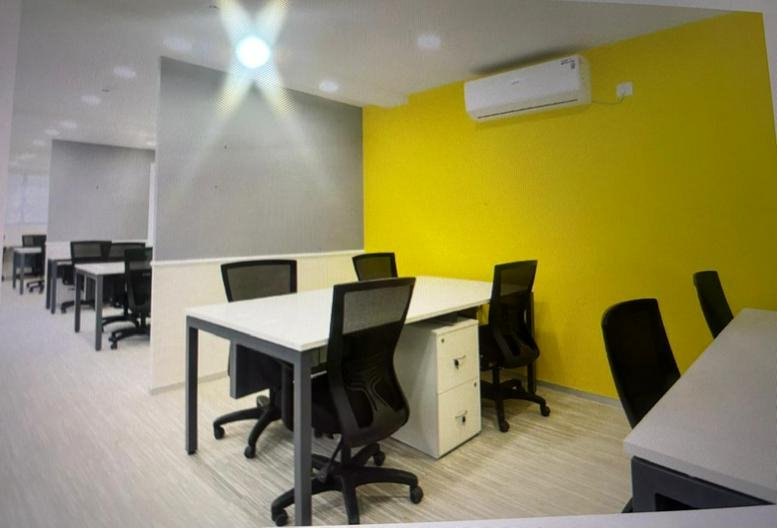 Spacious interior of 56, Pahari Road, Laxmi Nagar, Chhoti Pahari, Patna featuring white desks and a vibrant yellow wall.