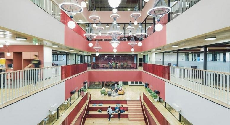 Spacious three-story atrium at 6 Jiuxianqiao Lu, Chaoyang District, Beijing featuring tiered seating and orb lighting.