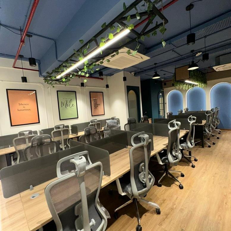 Modern office layout with wooden desks, ergonomic chairs, and greenery accents.
