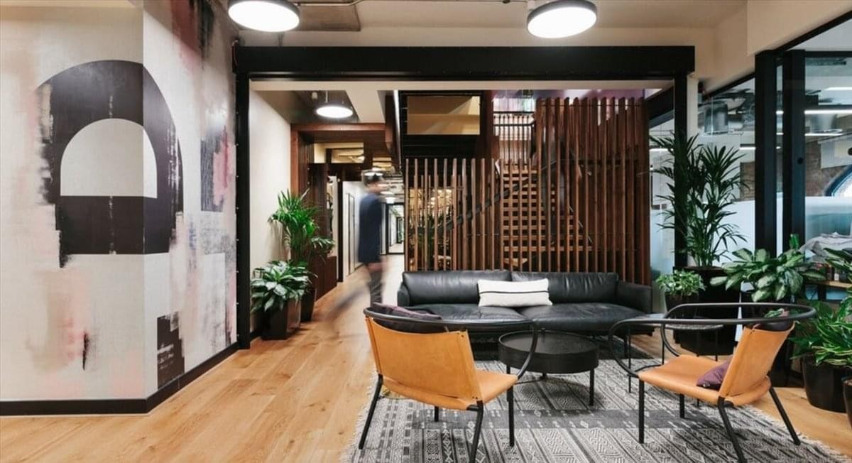 Spacious reception area with a feature wall mural, leather furniture, and wood floors at 9 Wangjing Jie.