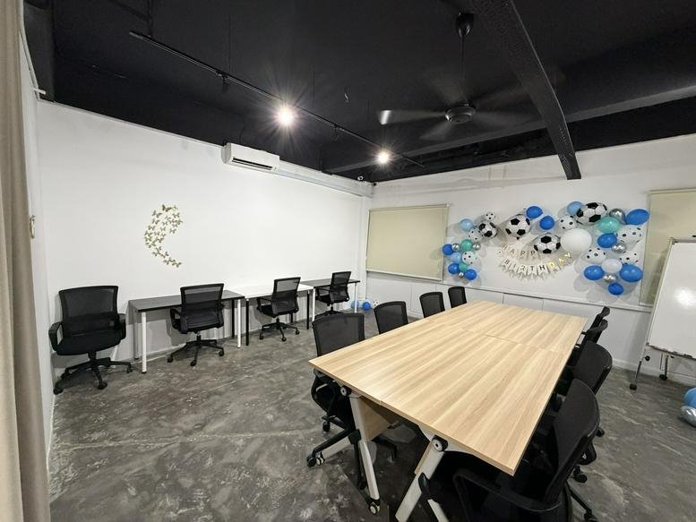 Spacious meeting room with a large wooden table, mesh chairs, and festive soccer-themed balloon decor.