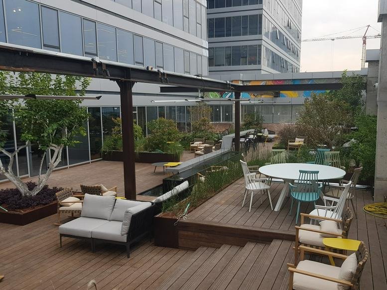 Spacious rooftop terrace at Alon Tower with wooden decking, seating areas, and greenery.