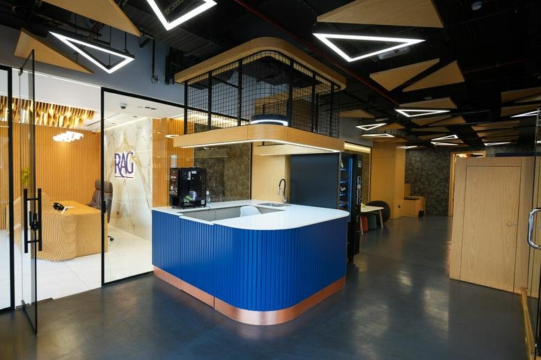 Lounge area with a blue counter, wood accents, and geometric light fixtures on a black ceiling.