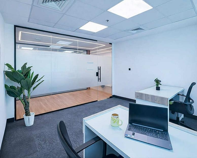 Bright private office at Al Jazeera Tower Building featuring frosted glass partitions and a laptop on a white desk.