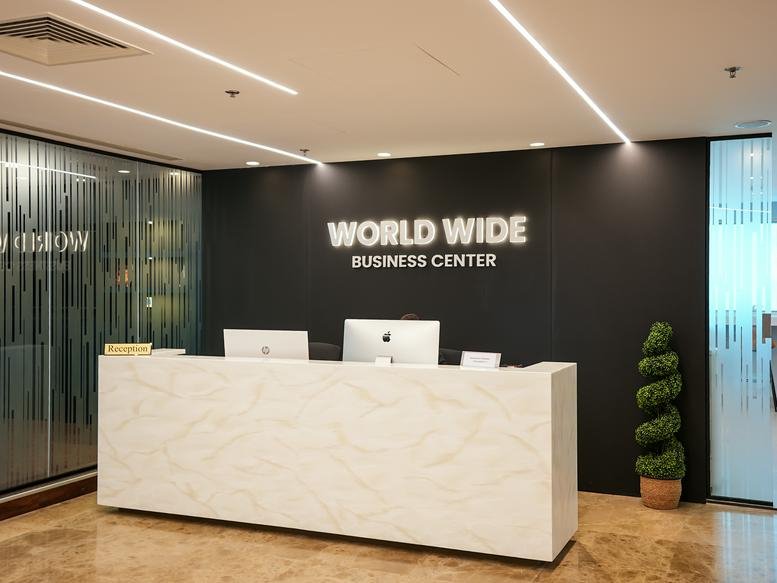 Reception area at Al Jazeera Tower with a marble desk and branded black feature wall.
