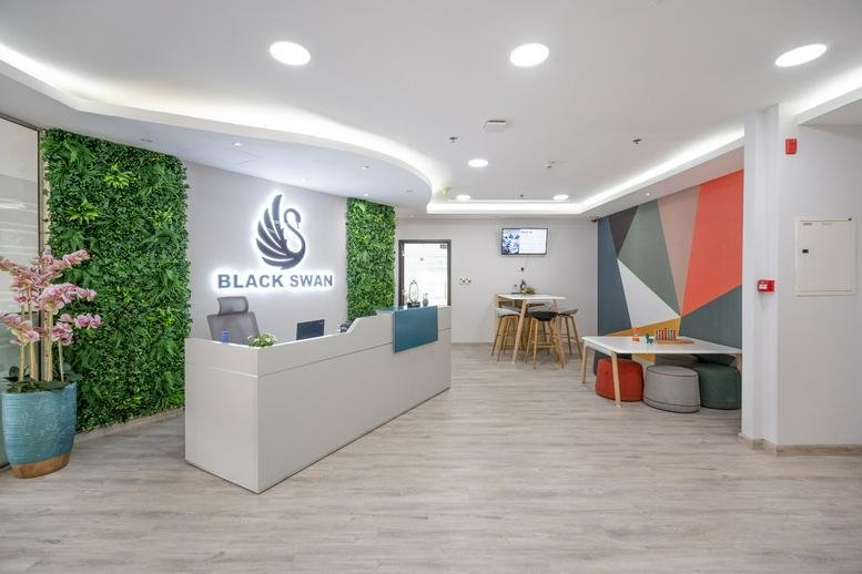 Bright reception area of Black Swan Business Center at Citadel Tower with green walls and a sleek white desk.