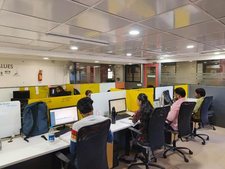 Wide view of a collaborative coworking area with several people working at desks.