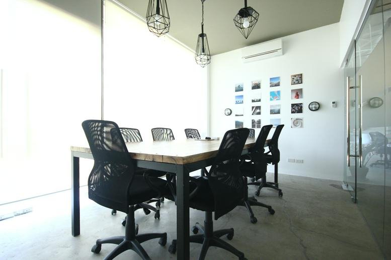A professional meeting room at Commercenter Alabang featuring a light wood table and modern mesh chairs.