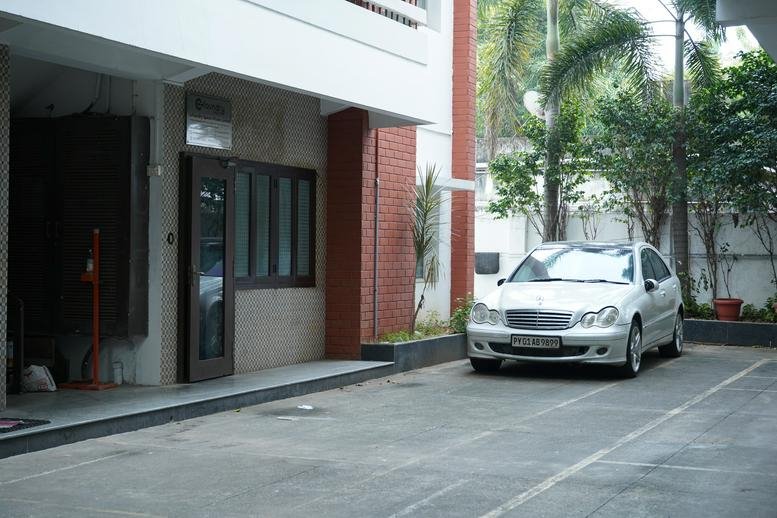 Exterior view of the white building entrance at Cofoundry Spaces with a car parked in front.