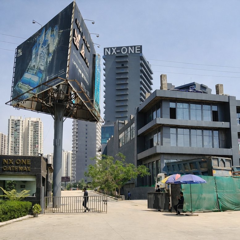 Exterior view of the NX One building in Greater Noida with a large billboard and modern facade.