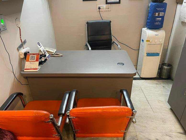 Functional workspace at SCF 30F, Bhai Randhir Singh Nagar, Ludhiana, featuring a grey desk and orange guest chairs.